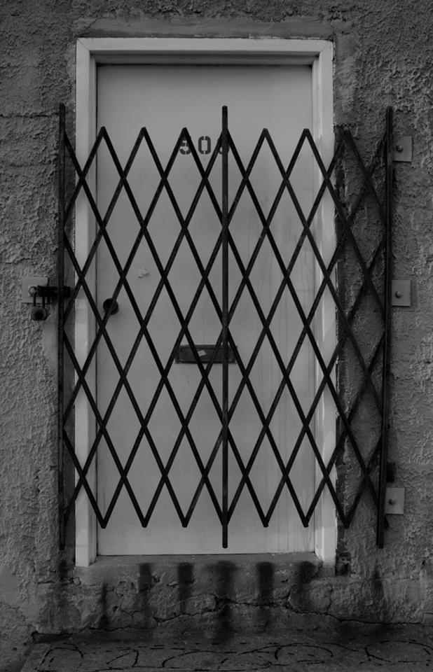 Black and white photograph of an abandoned gated door in NYC