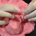 Child playing with homemade playdough at a table, shaping and molding dough with hands